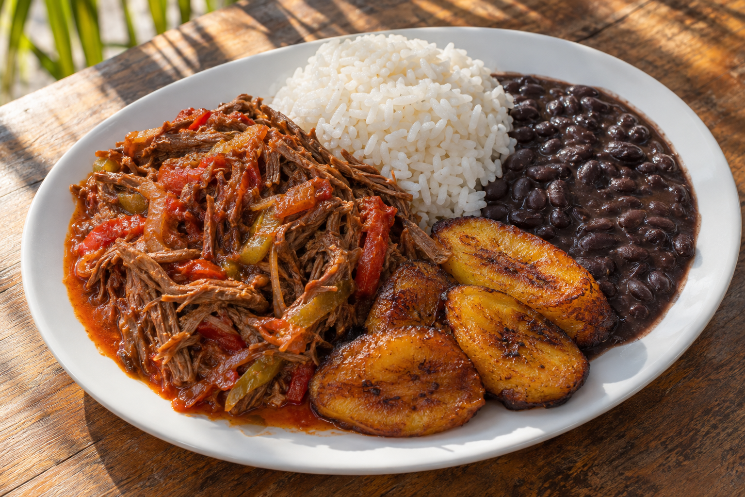 Plate of ropa vieja with white rice, black beans and fried sweet plantains