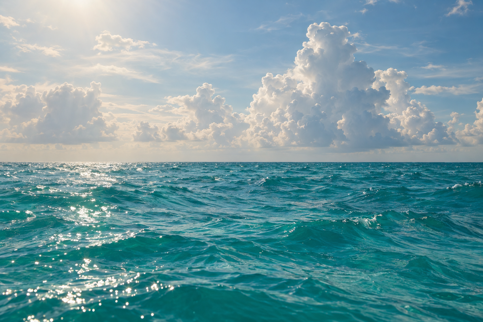 Warm turquoise Atlantic Ocean surface on a hazy summer day off South Florida with distant cumulus clouds building on the horizon